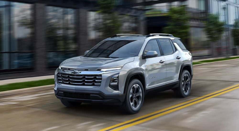 A silver 2025 Chevy Equinox driving down a city street