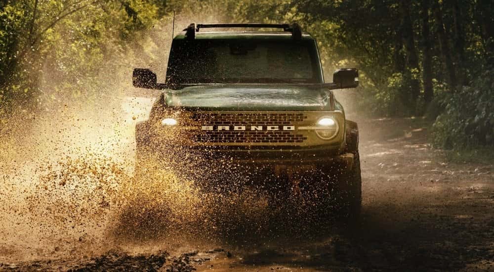 A black 2025 Ford Bronco off-roading in mud