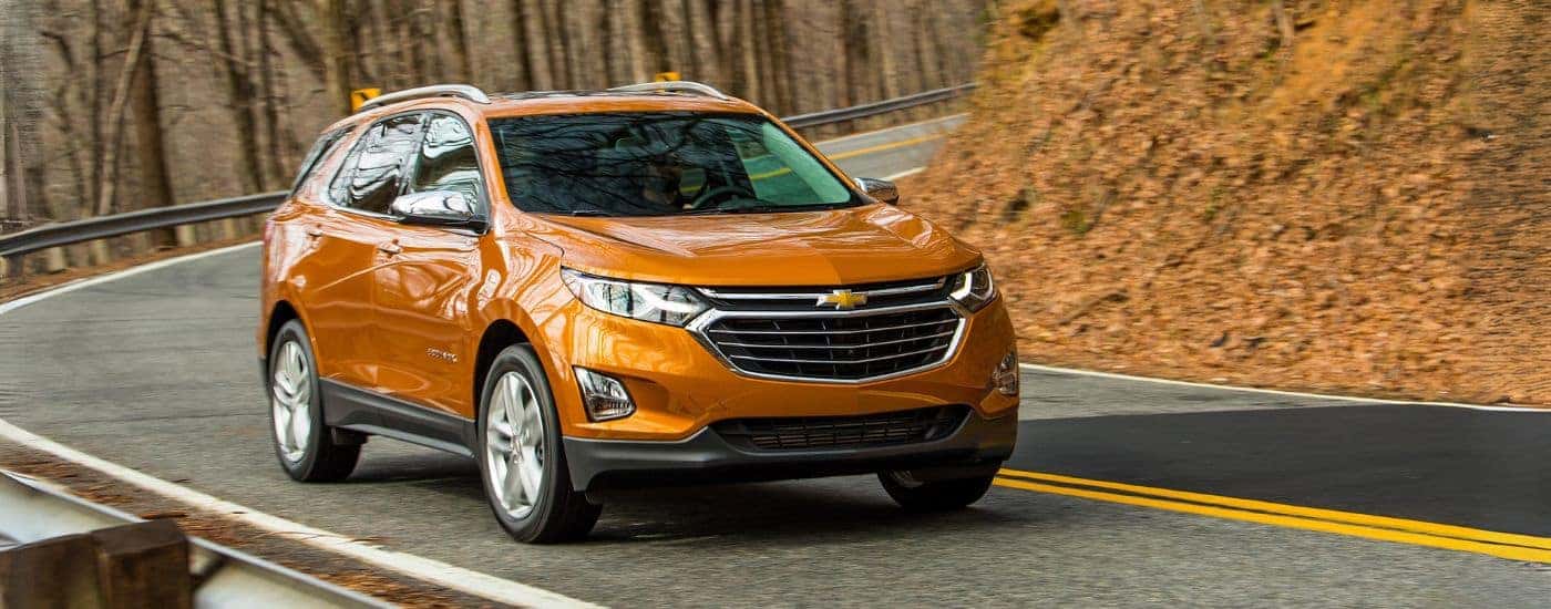 Orange 2018 Chevy Equinox driving around a bend.