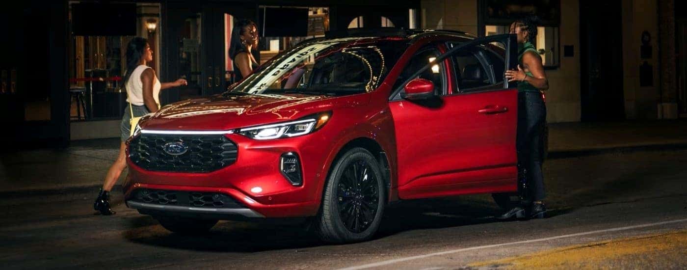 A red 2023 Ford Escape ST-Line is shown parked by a curb.