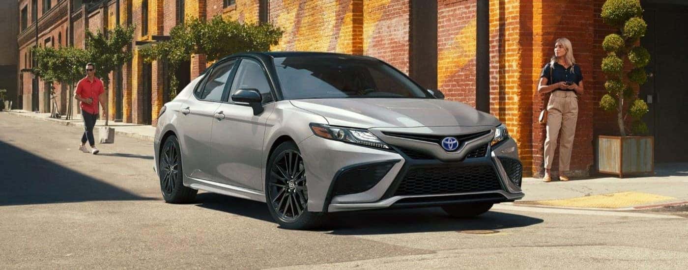 A silver 2023 Toyota Camry XSE is shown driving near a brick building