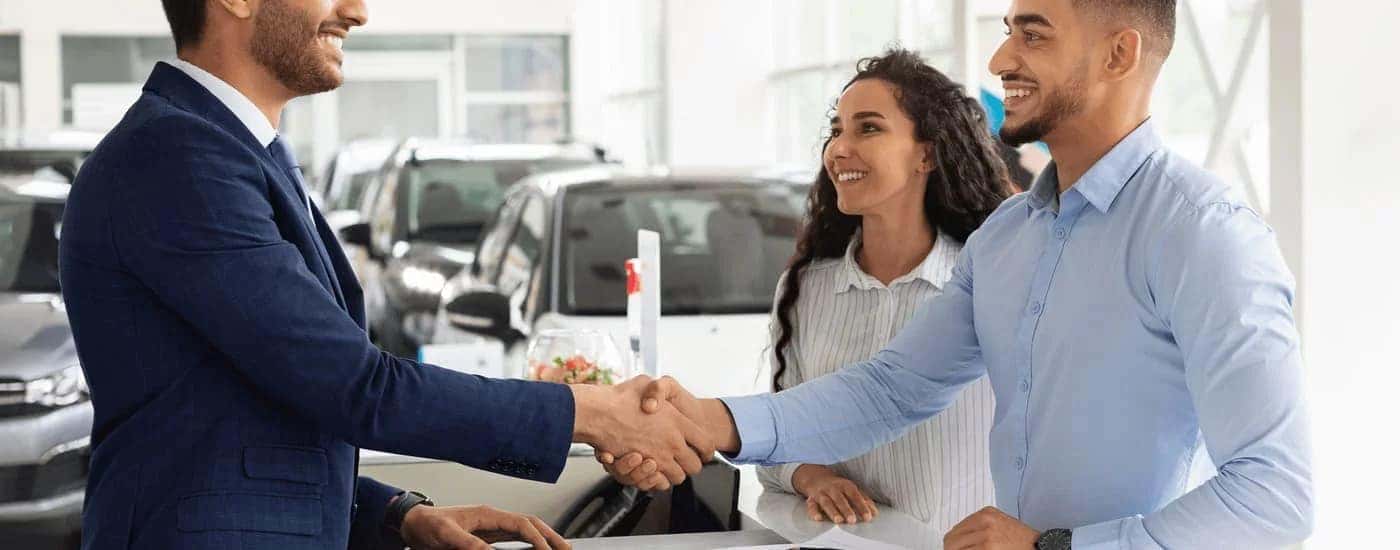 Salesman speaking to two customers about selling their car