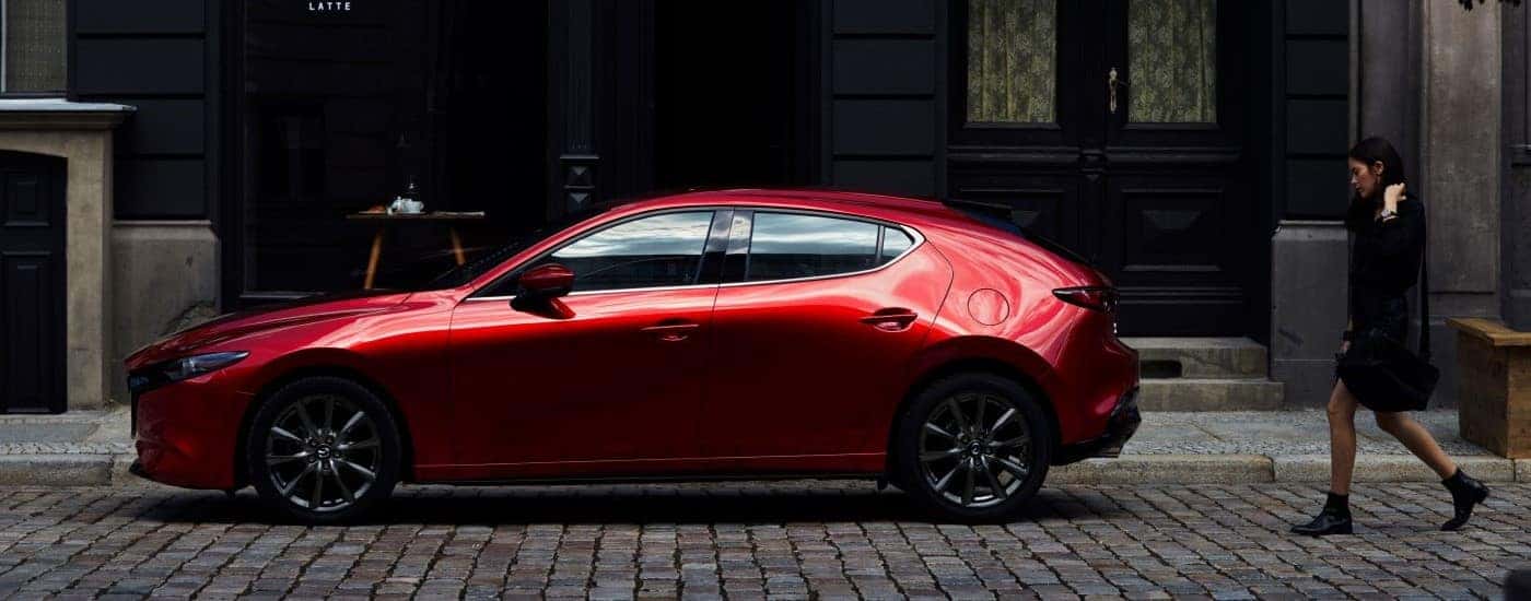 A red 2023 Mazda3 parked on cobblestone.