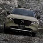 A green 2025 Mazda CX-5 shown parked on a rocky hill from the front.
