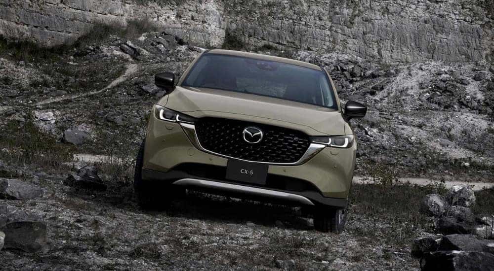 A green 2025 Mazda CX-5 shown parked on a rocky hill from the front.