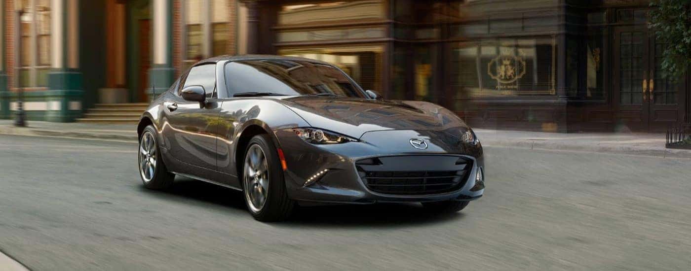 A grey 2023 Mazda Miata RF driving down a city street.