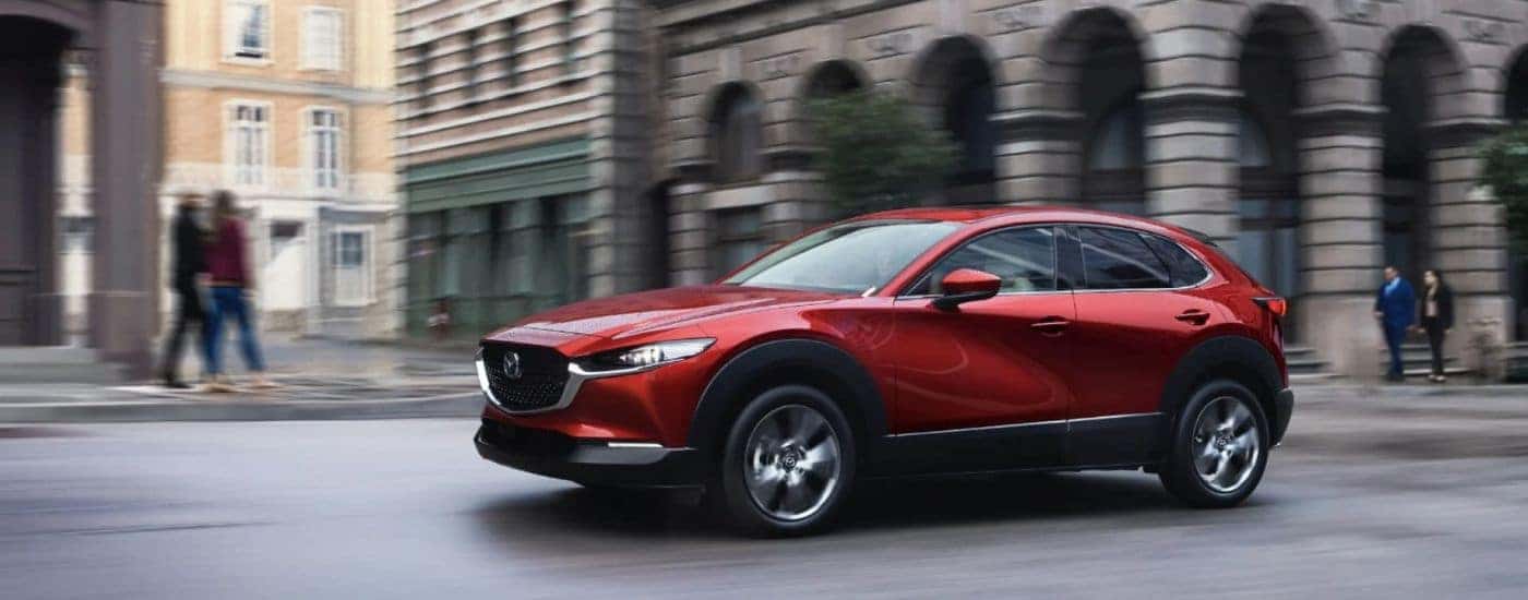 A red 2024 Mazda CX-30 driving in a city.