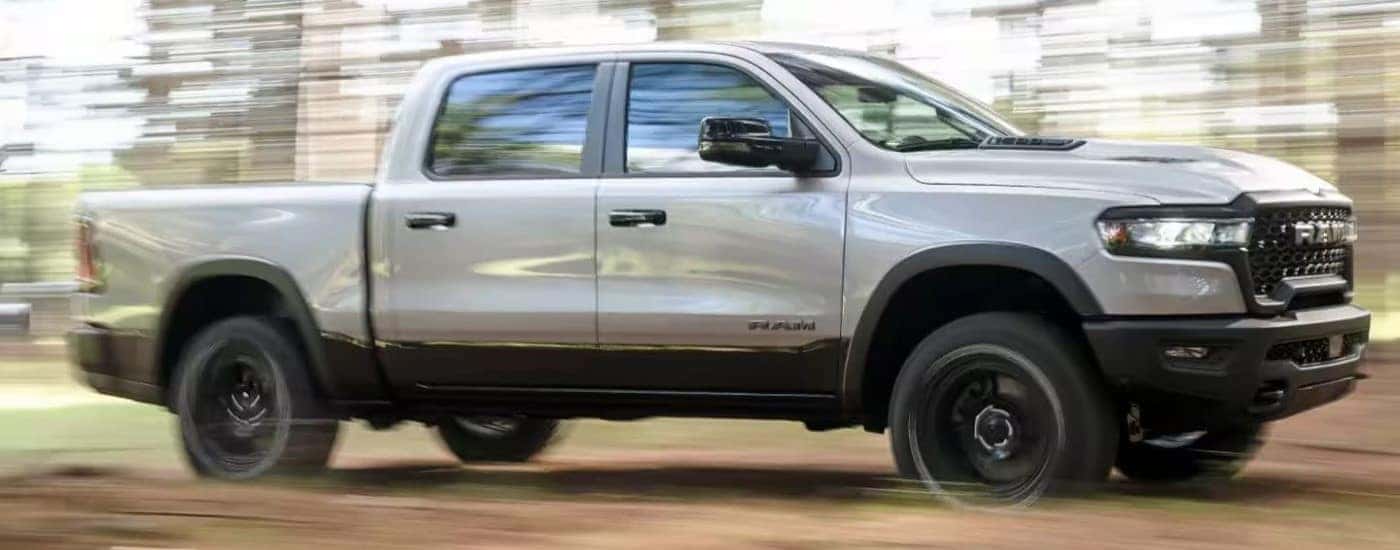 A silver 2025 Ram 1500 driving on a trail