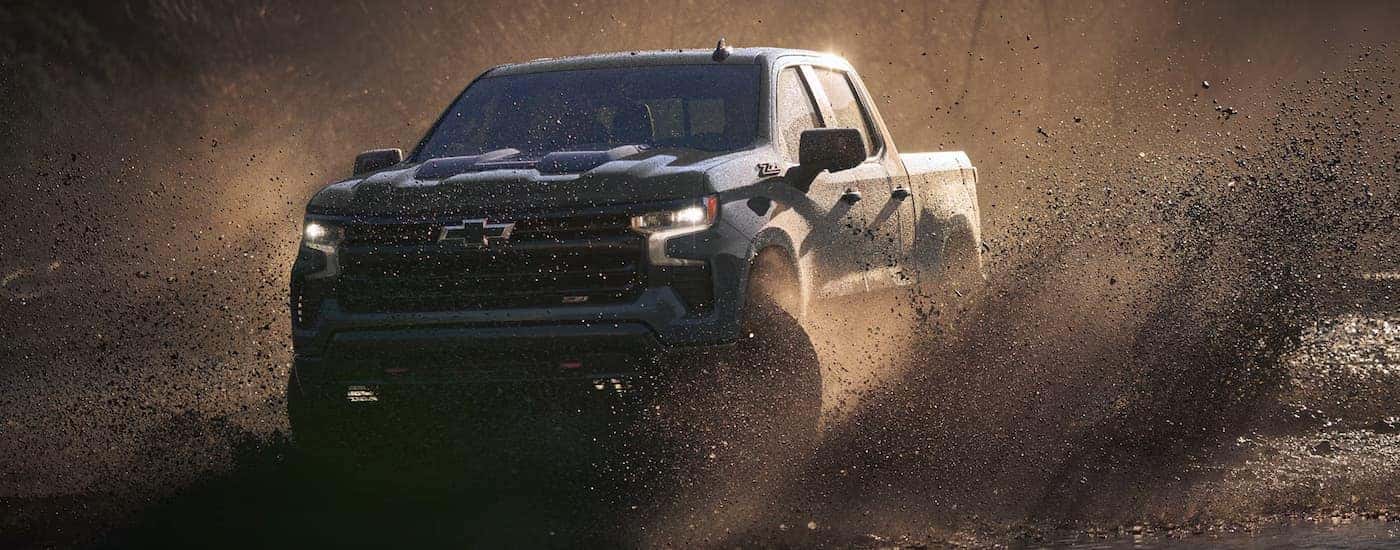 A black 2025 Chevy Silverado 1500 Z71 off-roading in mud
