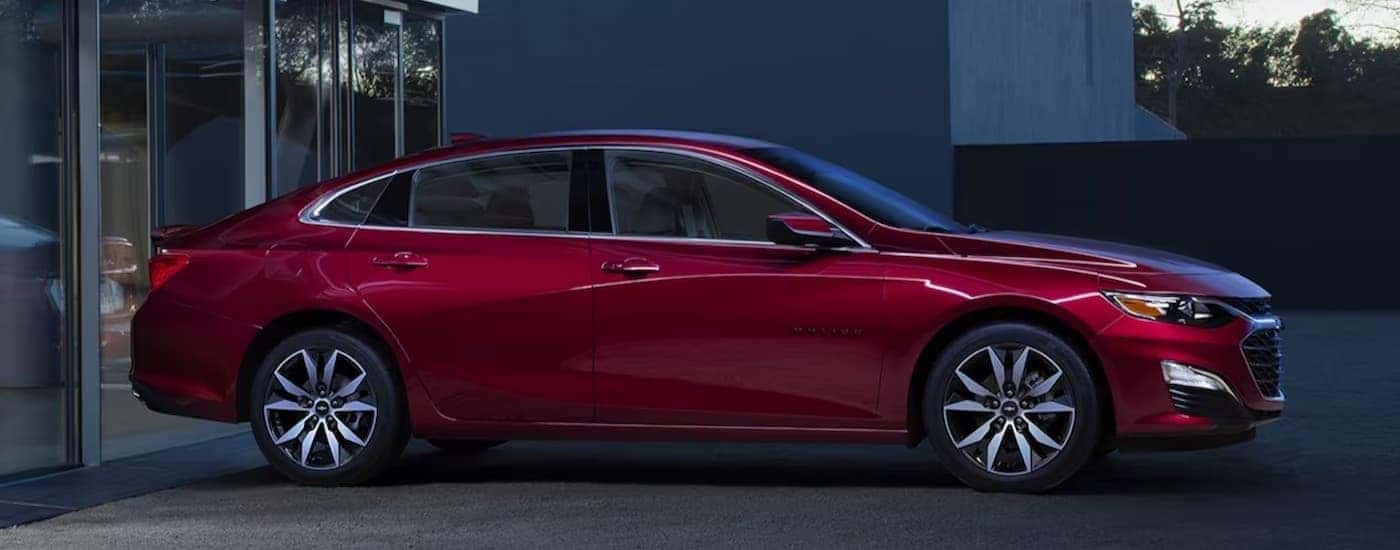 A red 202 Chevy Malibu parked near a house.