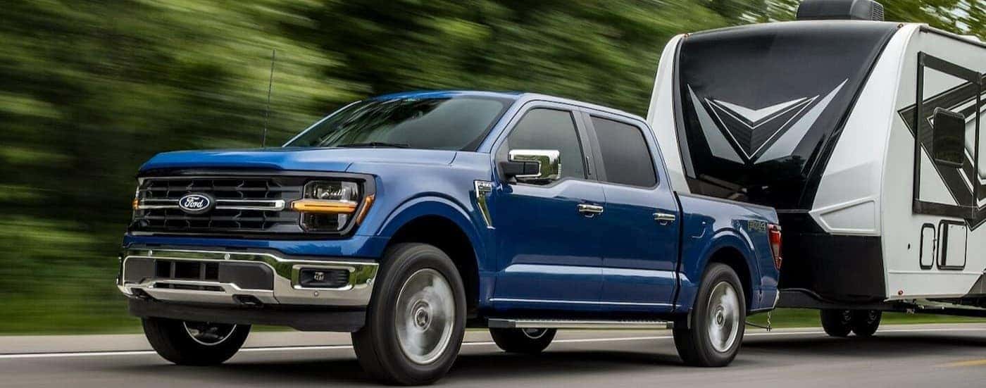 A blue 2024 Ford F-150 towing a trailer.