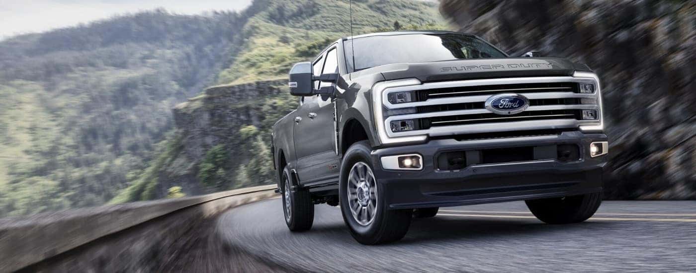 Black 2026 Ford F-350 Platinum Plus driving down a road.