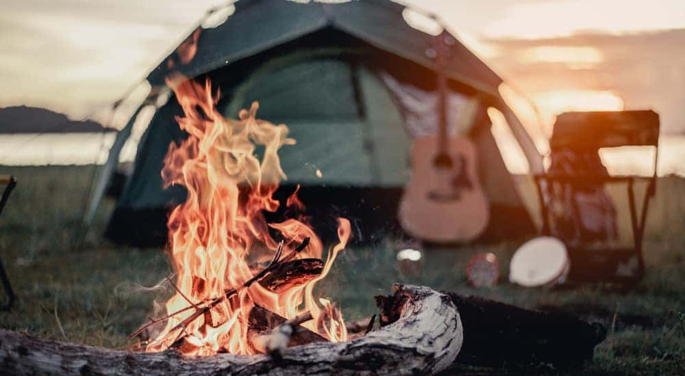 Orange fire in front of a green tent with a guitar leaning against it