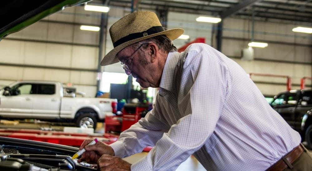 Roush, an older man, working under the hood of a vehicle in a garage