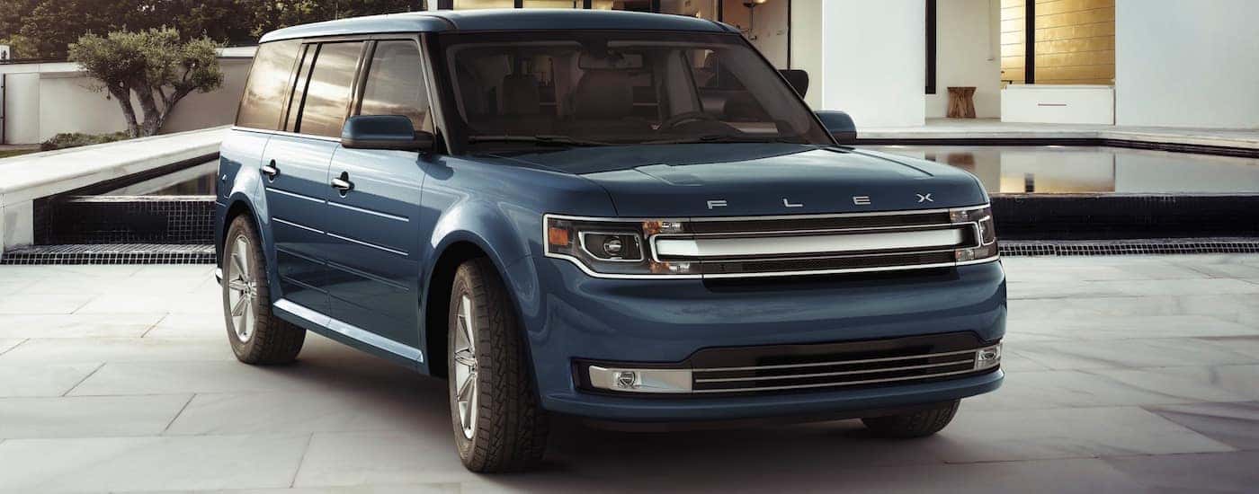A blue 2018 Ford Flex is parked at a modern home in front of a black pool.