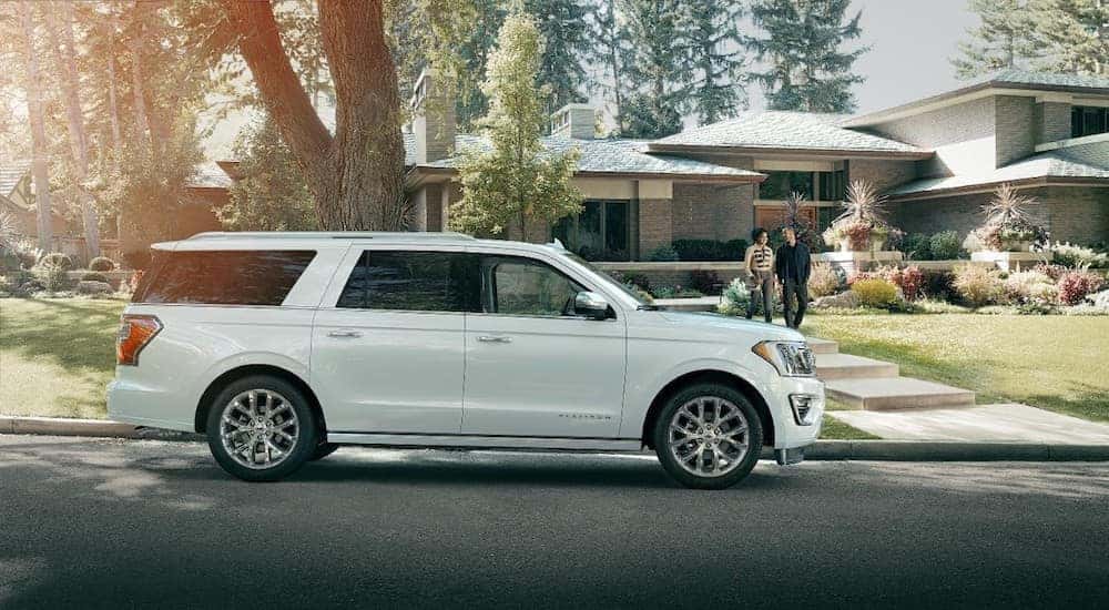 White 2018 Ford Expedition SUV parked in front of a stone house with a couple on the walkway 