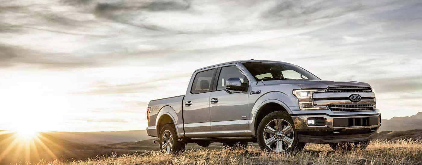 A silver 2018 Ford F-150 is parked off-road at sunset.