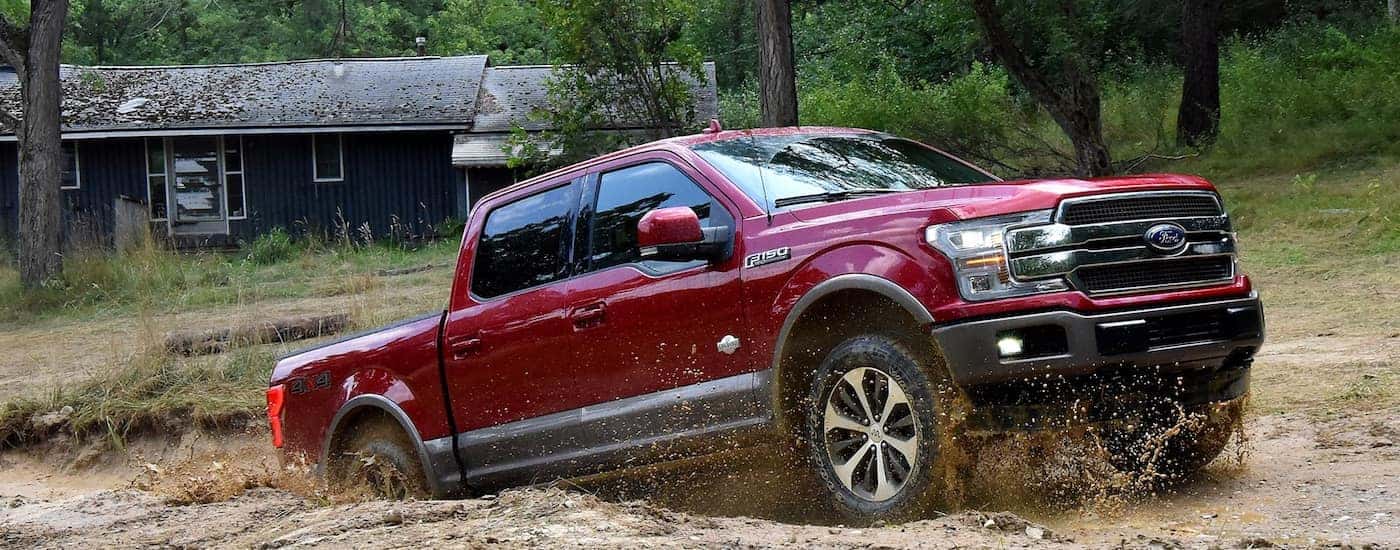 A red 2018 Ford F-150 is off-roading in the mud near Albany, NY.