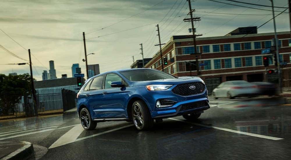 Blue 2019 Ford Edge SUV parked in the middle of an intersection surrounded by buildings and traffic lights