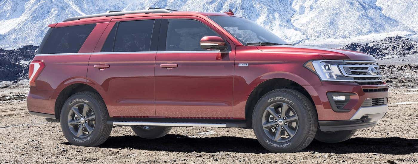 A red 2018 Ford Expedition is parked off-road with a blue sky and clouds above it.