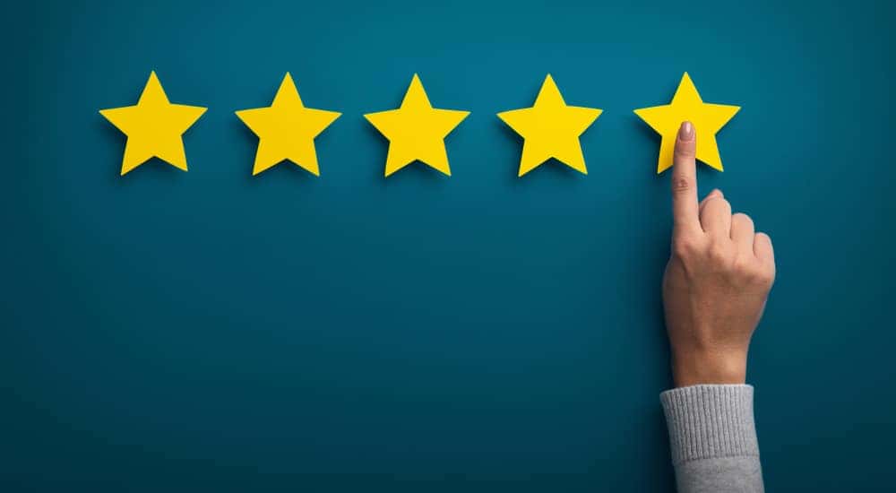 Person's hand pressing a fifth yellow star against a blue wall