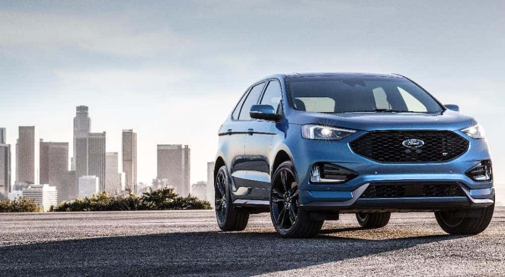 Blue 2019 Ford Edge SUV parked on cement in front of a city skyline