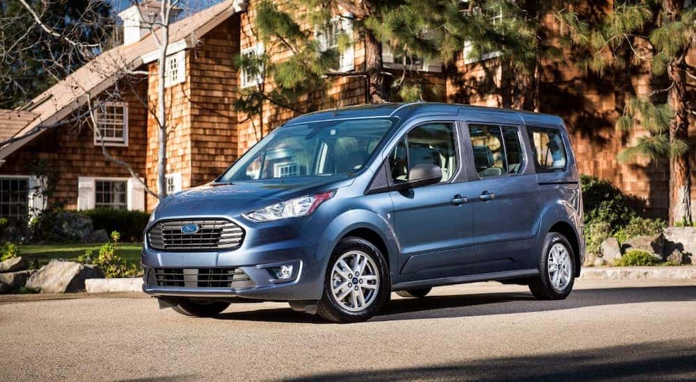 Blue 2019 Transit Connect Wagon parked in front of a brown house and trees