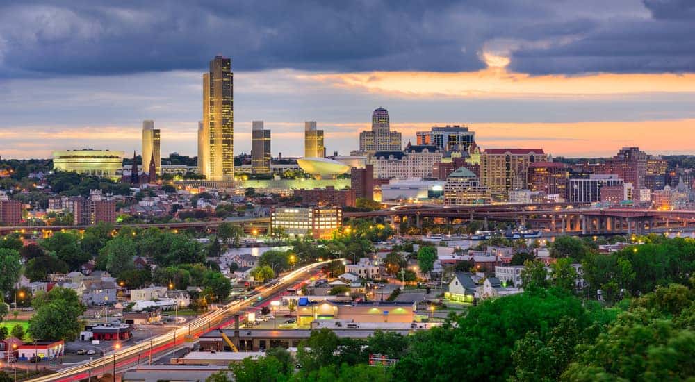 Lit-up Albany NY skyline with a sunset behind it close to a Ford dealership near you.