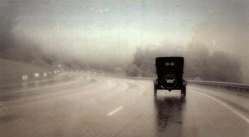 Rear of the Ford Model T driving on a paved road
