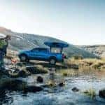 blue 2019 ford ranger holding kayak parked by a creek with man carrying another kayak