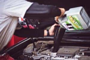 Service technician filling the oil reservoir in a vehicle with new oil