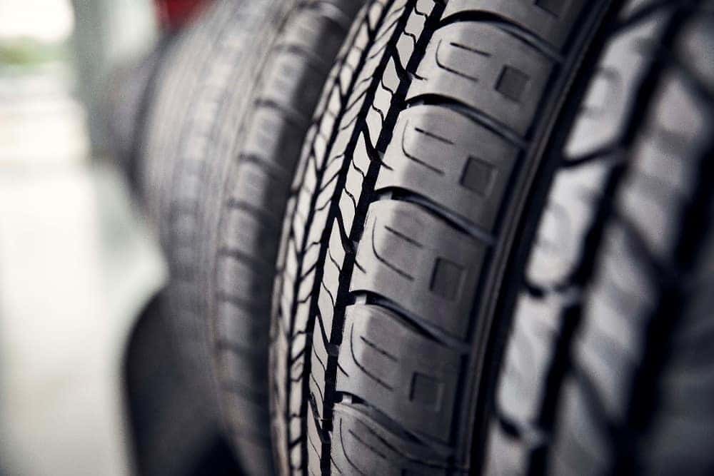 closeup picture of new black tires with full treads on a tire rack