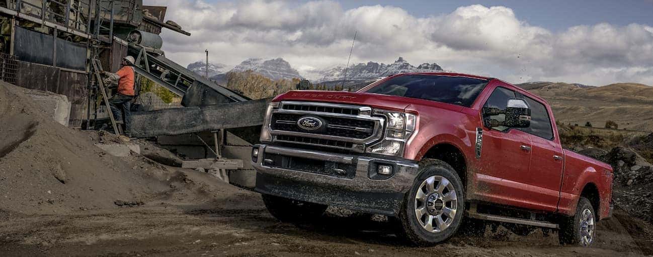 A red 2020 Ford Super Duty is parked on a dirt hill while men work next to it.