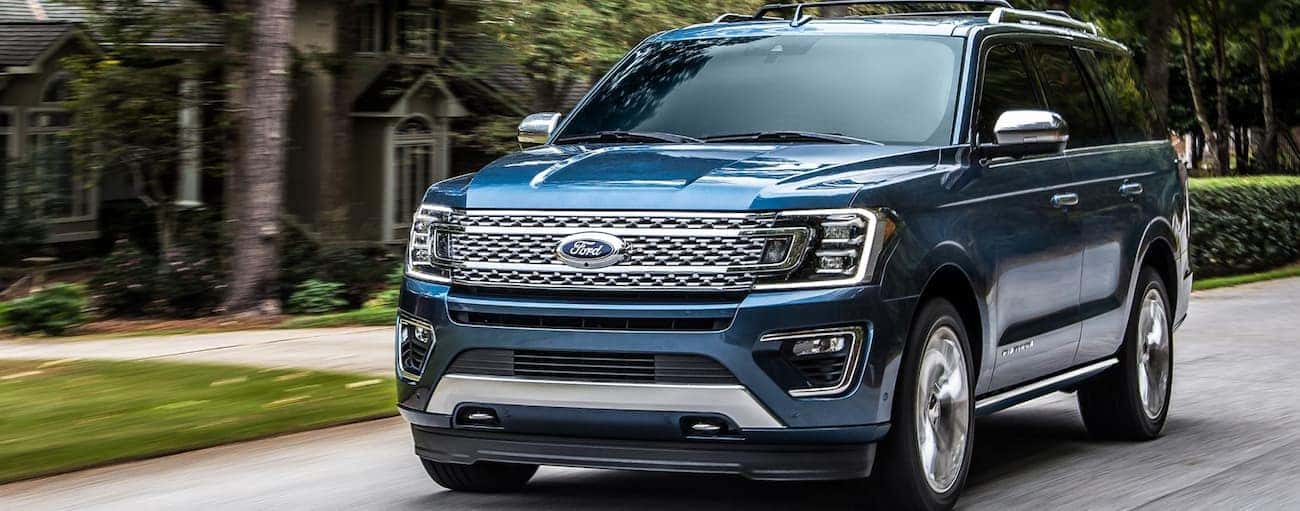 A blue 2020 Ford Expedition is driving on a road passing large houses near Albany, NY.