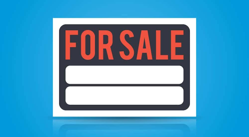 Black, white, and orange "FOR SALE" sign on a blue background