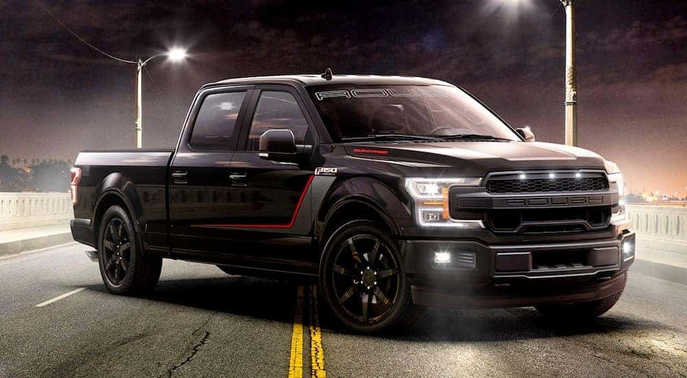 A black 2019 Roush F-150 Nitemare is parked in front of street lights at night.