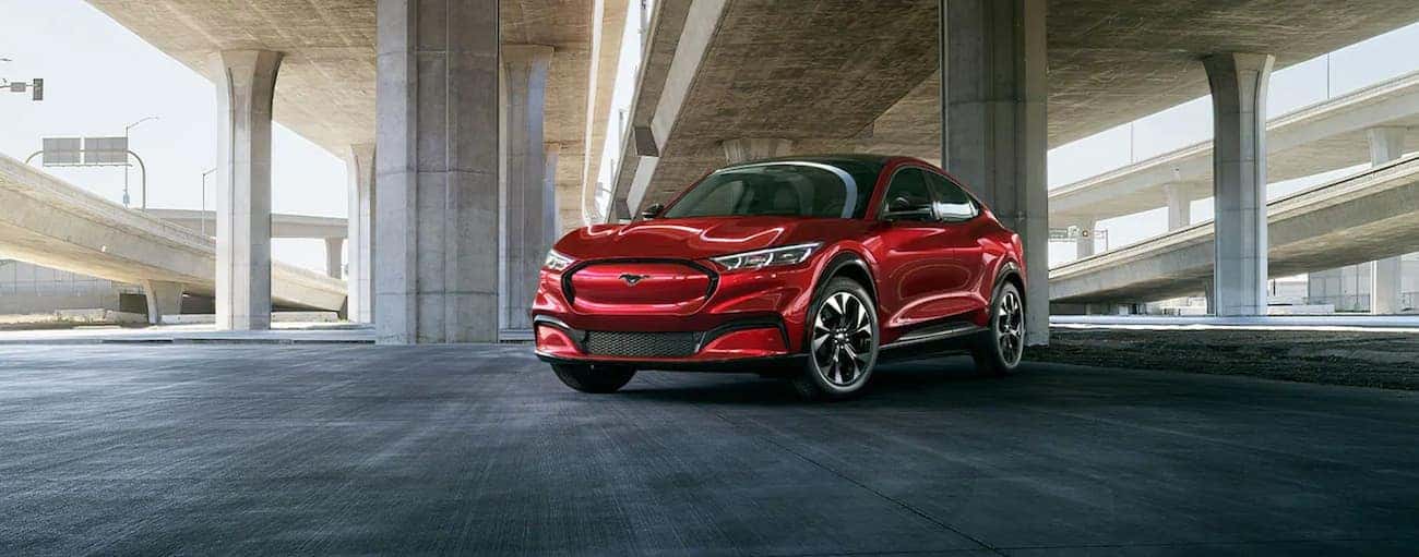 A red 2021 Ford Mustang Mach-E is parked under a concrete bridge near Albany, NY.