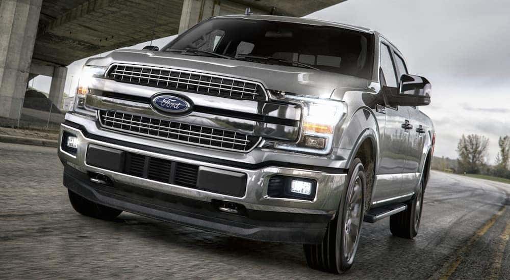 A silver 2018 Ford F-150, which is a popular option among used Ford trucks, is driving under a bridge near Albany, NY.