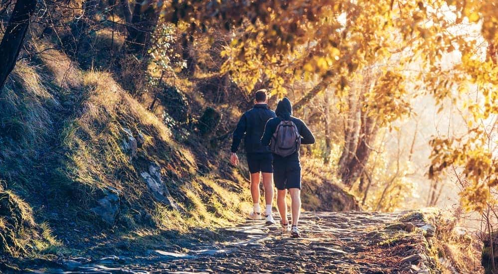A father and son are hiking on a dirt trail.
