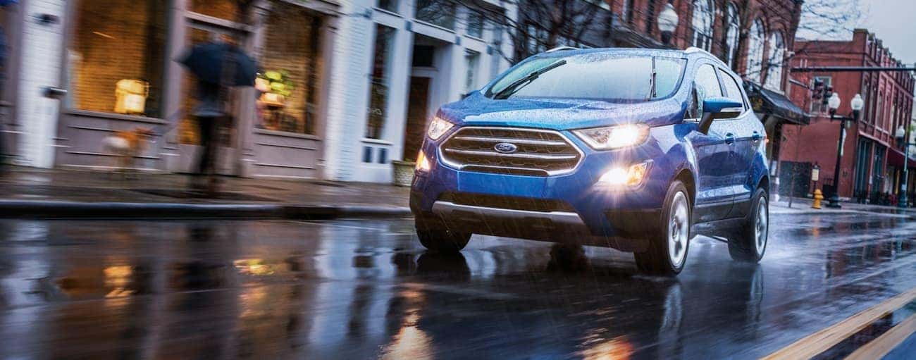 A blue 2020 Ford EcoSport is driving in the rain on a city street near Indiana, PA.