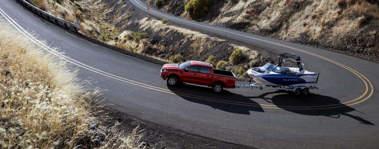 A red 2020 Ford Ranger is towing a boat up a winding road near Albany, NY.