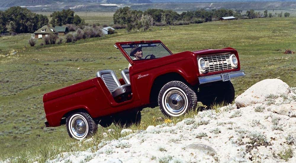 A red 1966 Ford Bronco with no roof is shown climbing a hill.