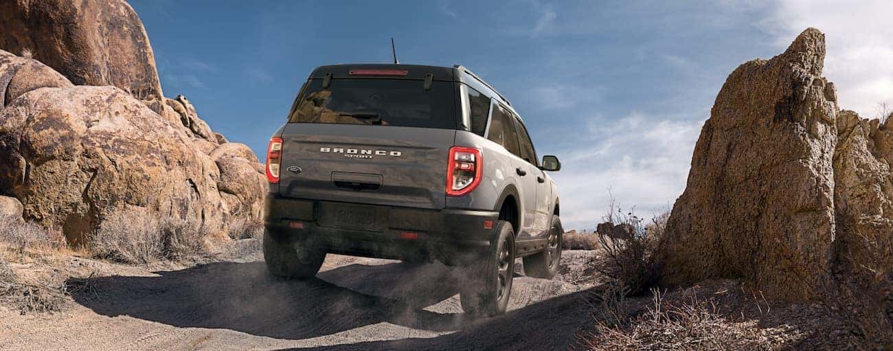 A grey 2021 Ford Bronco Sport is driving on a dirt trail in the desert, shown from the rear.