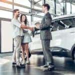 A couple is shaking hands with a salesman at a local car dealership in Albany, NY.
