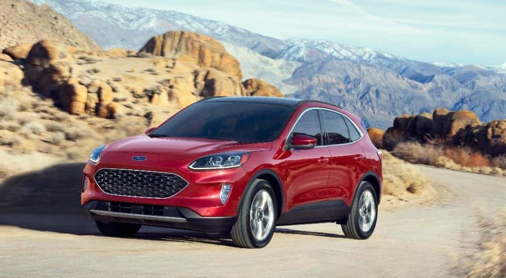 Red 2020 Ford Escape SUV parked on a dirt road with mountains, cliffs, and rocks surrounding it