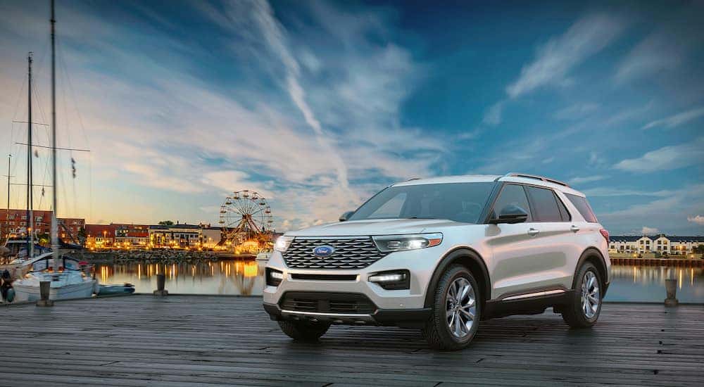 White 2020 Ford Explorer SUV parked on a dock in front of water, with lights, buildings, and a ferris wheel in the background