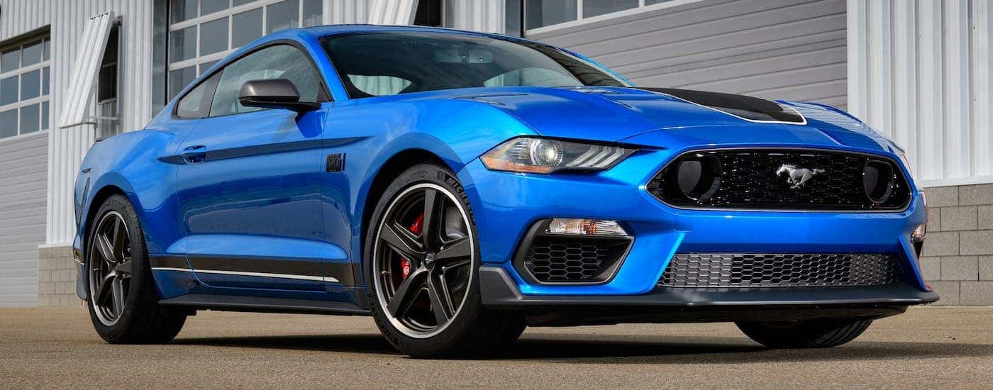 A blue 2021 Ford Mustang Mach 1 is parked in front of a metal garage near Albany, NY.