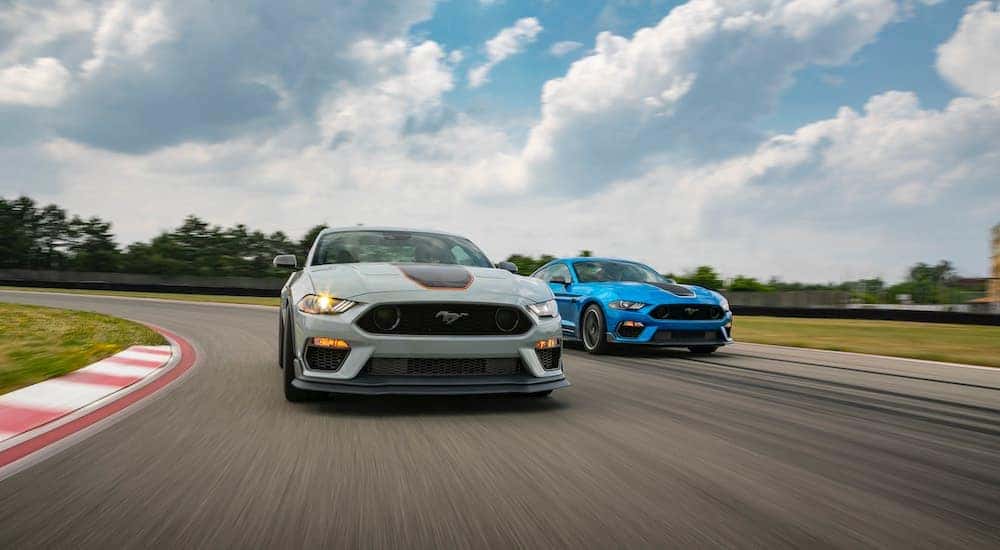 A grey and a blue 2021 Ford Mustang Mach 1 are racing on a track.