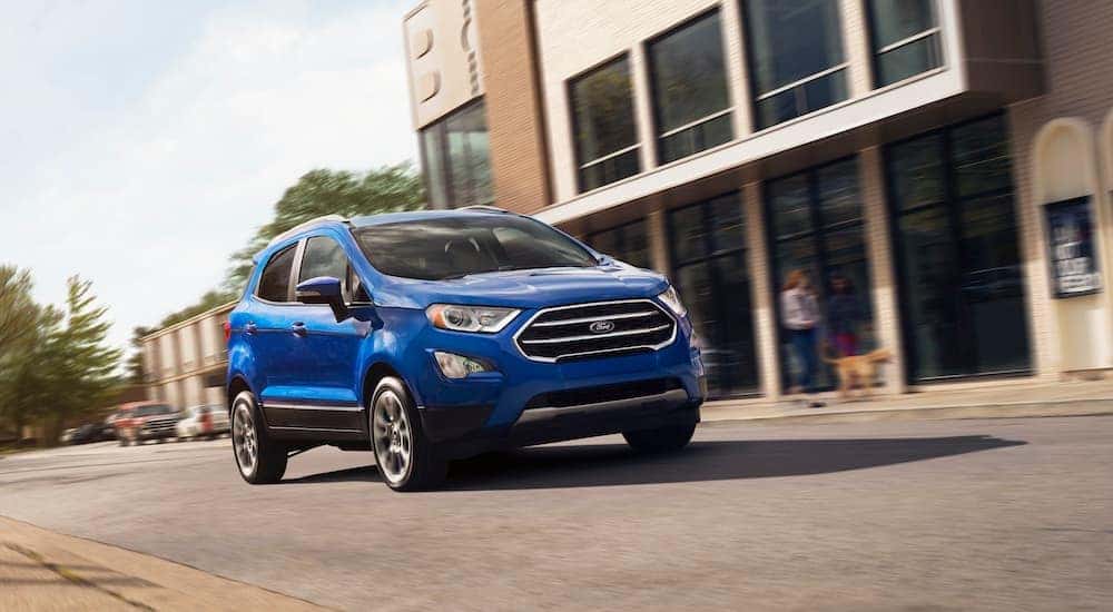 A blue 2019 used Ford EcoSport is driving on a city street near Albany, NY.