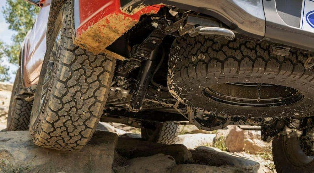 A red 2021 Ford Ranger Tremor Lariat is shown from underneath while crawling over rocks.